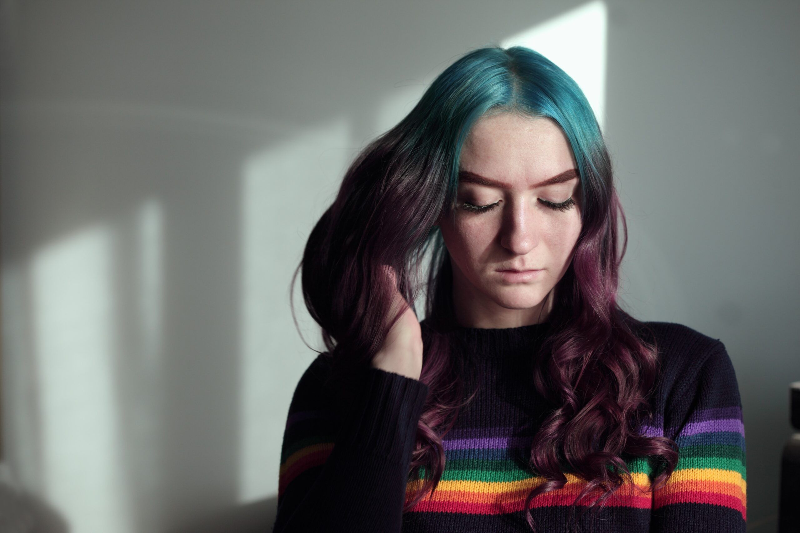 Young woman wearing a rainbow coloured jumper sitting inside